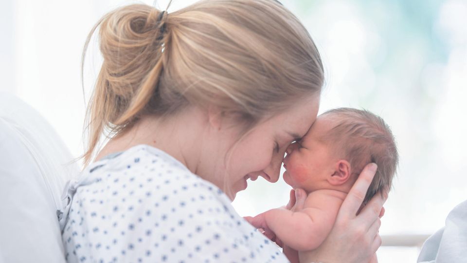 Eine Mutter hält glücklich ihr Neugeborenes im Arm