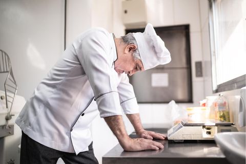 Koch beugt sich besorgt über einen Tisch