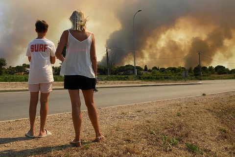18. August 2021, Südfrankreich: Touristen beobachten, wie Rauch den Himmel verdunkelt, der von Waldbränden ausgeht