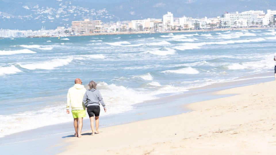 Ein Paar geht im Frühjahr am Strand von Playa de Palma auf Mallorca spazieren