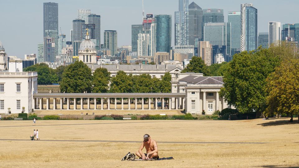 London August 2022: Ein Mann sonnt sich auf vertrocknetem Gras im fast leeren Greenwich Park