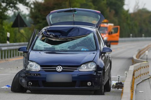 Ein dunkelblauer VW steht mit zerschmetterter Windschutzscheibe auf der linken Spur einer Autobahn