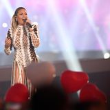 Während Helene Fischer auf der Bühne singt, halten Fans rote Herz-Luftballons hoch