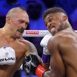 Ein weißer Boxer trifft mit links seinen schwarzen Gegner am Unterkiefer