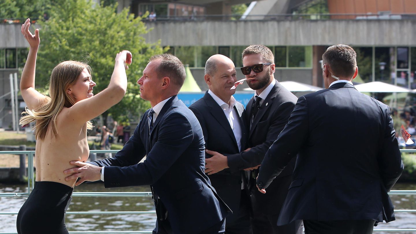 Mit offenbar geübtem Griff rückt der Personenschützer der Demonstrantin zu Leibe