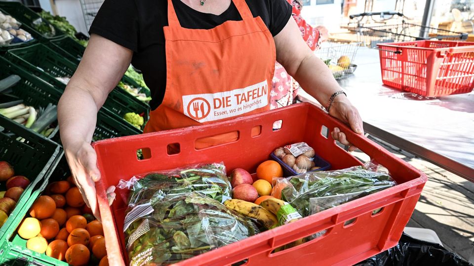 Eine Tafelmitarbeiterin im trägt eine Kiste mit Gemüse