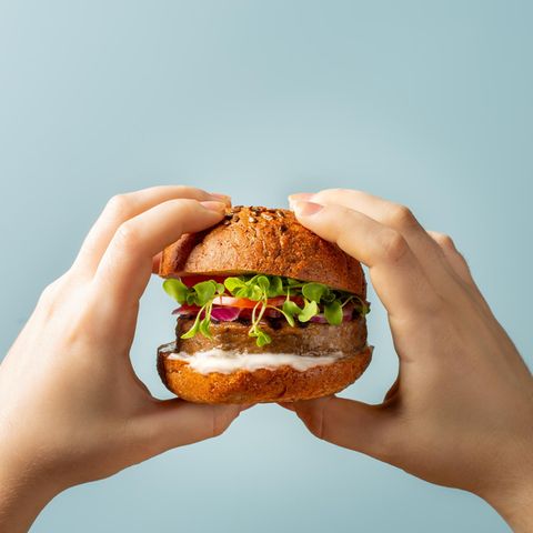 Zwei Hände halten einen vegetarischen Burger