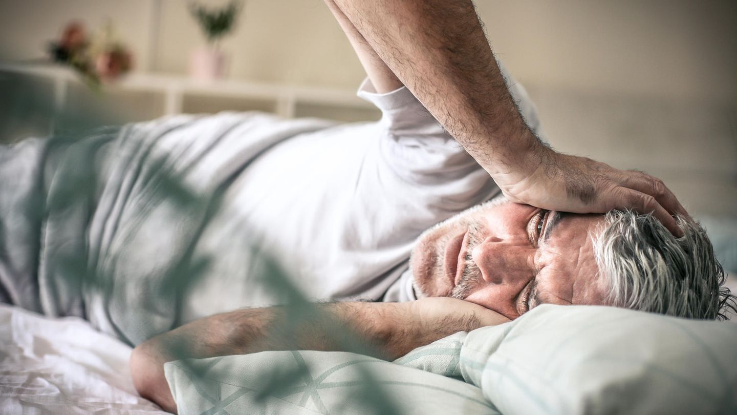 Migräne Mann liegt mit Migräne im Bett