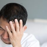 Mann fasst sich an den Kopf er Clusterkopfschmerzen hat