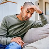 Mann fasst sich an die Stirn und hat Kopfschmerzen