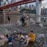 Menschen sitzen in einem flachen Wasserbecken im Flussbett des Flusses Jialing