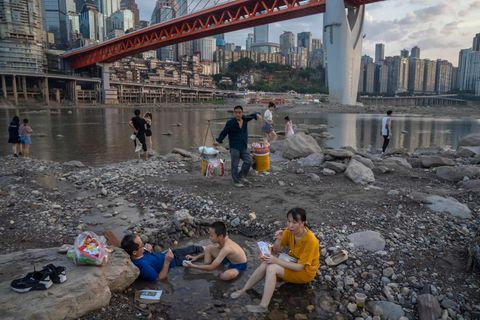 Menschen sitzen in einem flachen Wasserbecken im Flussbett des Flusses Jialing