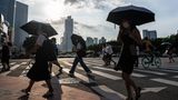 Menschen laufen mit Regenschirmen durch die chinesische Stadt Guangzhou