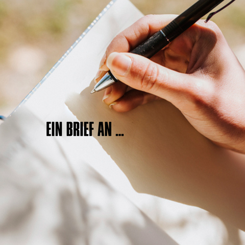 Eine Hand setzt zum Schreiben in einem Buch an