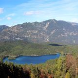 Der Bayerische Wald mit einem Bergsee und den Alpen im Hintergrund.