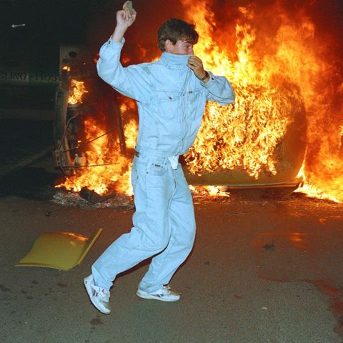 Ein Demonstrant in Rostock-Lichtenhagen wirft Steine auf die Polizei