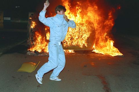 Ein Demonstrant in Rostock-Lichtenhagen wirft Steine auf die Polizei