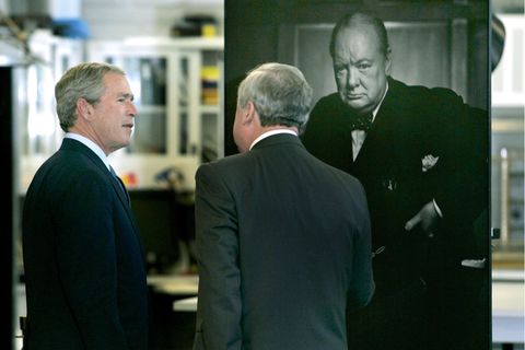 Zwei Männer, einer davon George W. Bush, stehen vor einem Fotoporträt von Winston Churchill