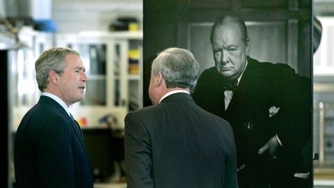 Zwei Männer, einer davon George W. Bush, stehen vor einem Fotoporträt von Winston Churchill