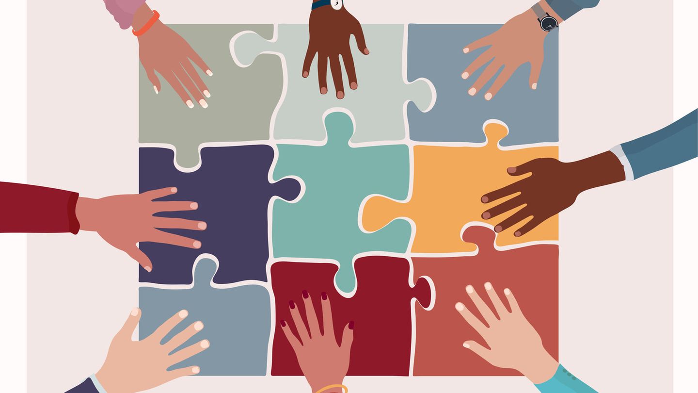 Illustration: Hände verschiedener Hautfarben liegen auf Puzzleteilen Illustration: Hände verschiedener Hautfarben liegen auf Puzzleteilen