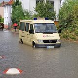 Einsatzfahrzeuge von Feuerwehr und Rettungsdiensten müssen sich durch überschwemmte Straßen kämpfen