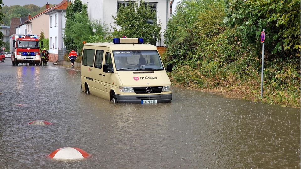 Einsatzfahrzeuge von Feuerwehr und Rettungsdiensten müssen sich durch überschwemmte Straßen kämpfen