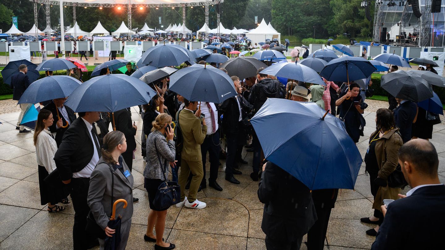 Gäste versuchen unter Schirmen beim Bürgerfest des Bundespräsidenten im Park von Schloss Bellevue ins Gespräch zu kommen