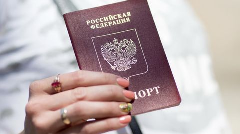 Ein russischer Pass in der Hand einer Reisenden. Europa streitet über ein Visastopp