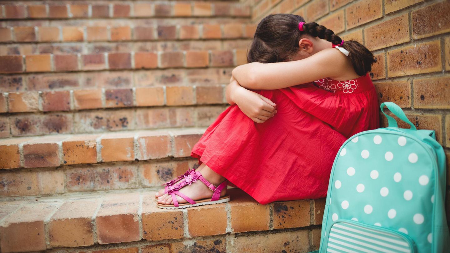 Ein Mädchen sitzt weinend auf einer Treppe