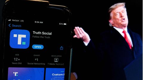 Ein Bild von Donald Trump steht neben der "Truth Social"-App