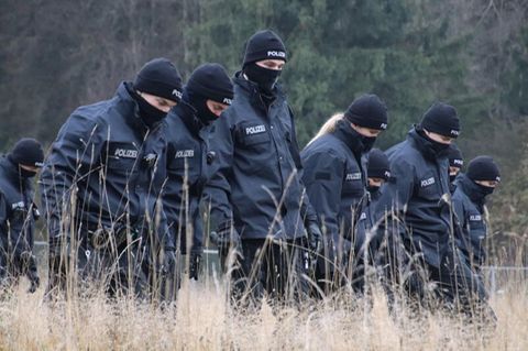 Polizeibeamte suchen auf einer Wiese Spuren, nachdem in der Nähe des Flughafens Memmingen eine Leiche gefunden wurde