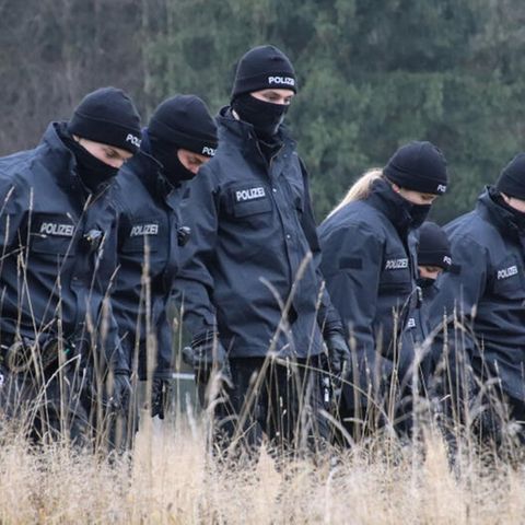 Polizeibeamte suchen auf einer Wiese Spuren, nachdem in der Nähe des Flughafens Memmingen eine Leiche gefunden wurde