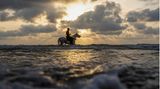 Ein Mann reitet auf seinem Pferd im Mittelmeer, während die Sonne in Gaza-Stadt untergeht