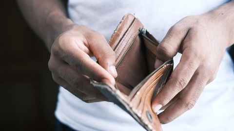 Ein Mann hält ein leeres Portemonnaie auf.