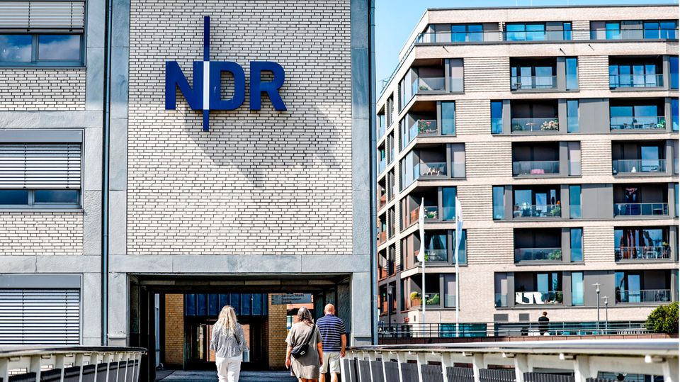 Schleswig-Holstein, Kiel: Passanten gehen vor der Einfahrt zum Landesfunkhaus Schleswig-Holstein des NDR entlang