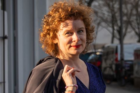 Tina Molin schreibt die stern-Kolumne Sex über 40. Sie trägt Locken und eine Jacke über der Schulter und lächelt