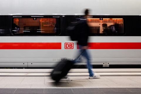 Mann mit Koffer geht an einem ICE vorbei