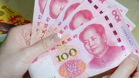 China: Eine Frau hält Geldscheine in den Händen