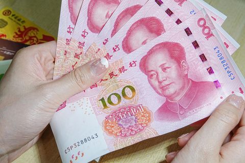 China: Eine Frau hält Geldscheine in den Händen