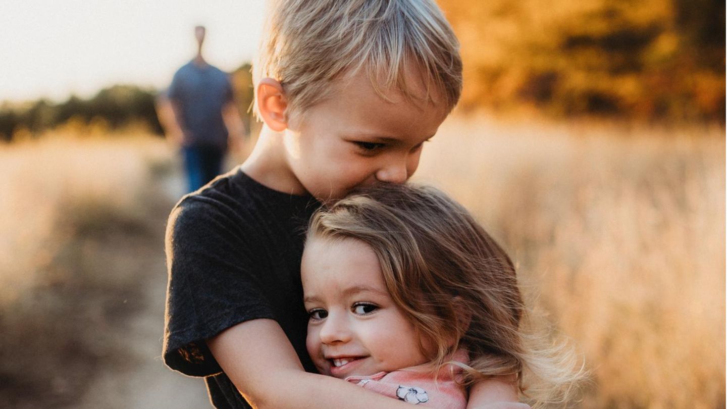 Ein Junge hält seine kleine Schwester im Arm.