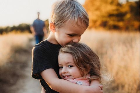 Ein Junge hält seine kleine Schwester im Arm.