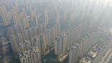 Zhenjiang, China. Die Wolkenkratzer der chinesischen Metropole werden von einem Nebelschleier umhüllt – der sich aber langsam lichtet. Die Gebäude gehören dem Unternehmen Garden Holding, das wegen des aktuellen Chaos auf dem chinesischen Immobilienmarkt 96 Prozent seiner Gewinne einbüßt.