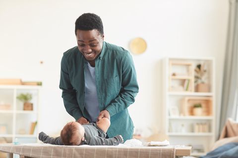 Vater wickelt sein Baby auf dem Wickeltisch mit Heizstrahler