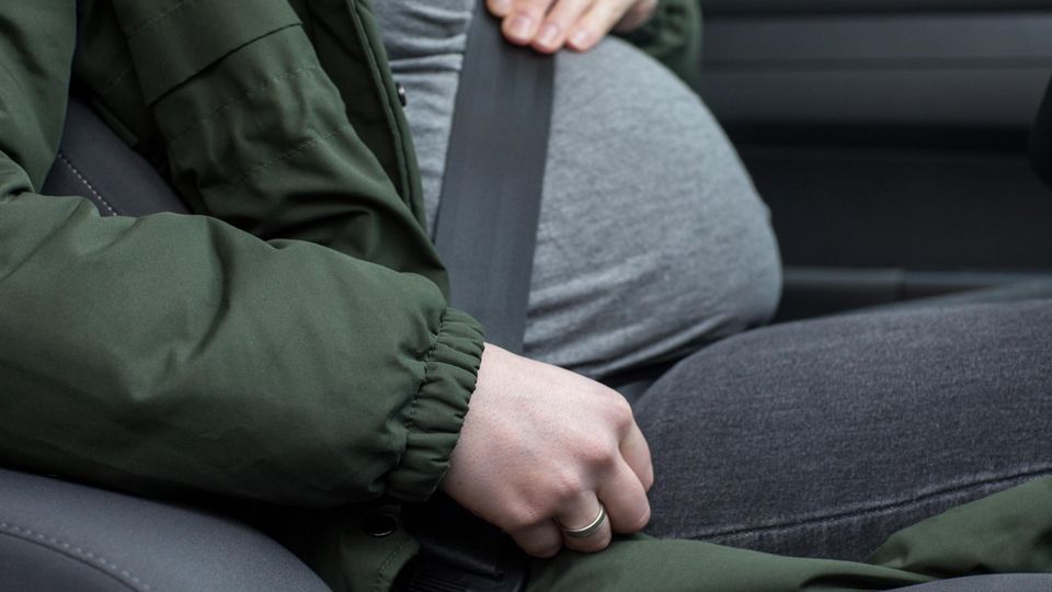 Eine schwangere Frau sitzt angeschnallt in einem Auto