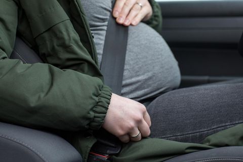 Eine schwangere Frau sitzt angeschnallt in einem Auto