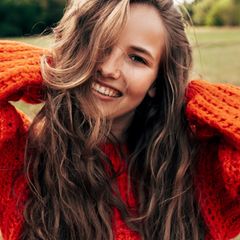 Eine junge Frau mit einem gestrickten orangefarbenen Pullover