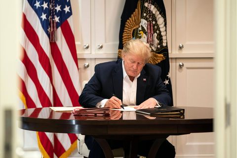 Donald Trump schreibt auf einem Blatt Papier