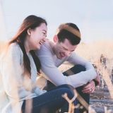 Eine Frau und ein Mann sitzen auf einem Steg und lachen.