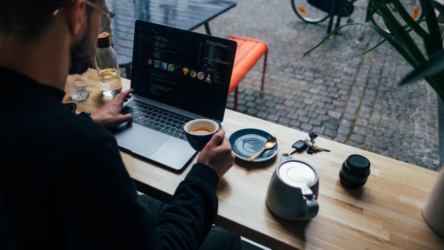 Ein Mann sitzt mit dem Laptop beim Frühstück.