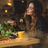 Eine Frau isst genüsslich Pasta.